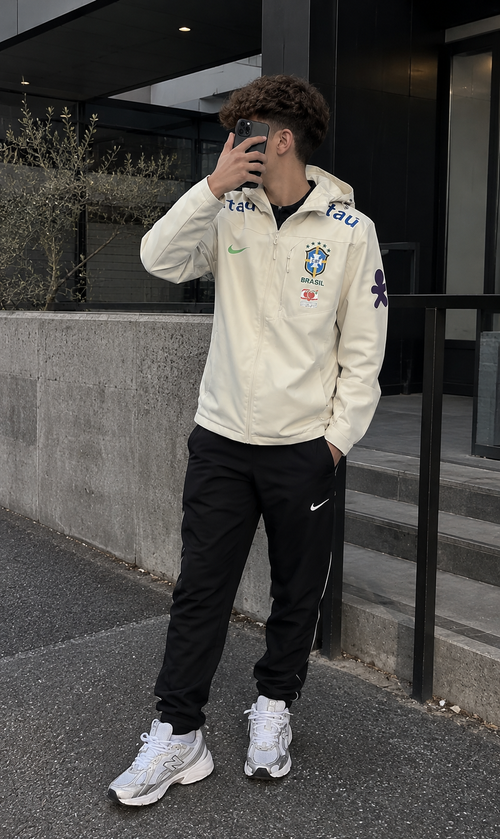 Coupe-vent Brésil crème porté avec un jogging noir et des baskets blanches